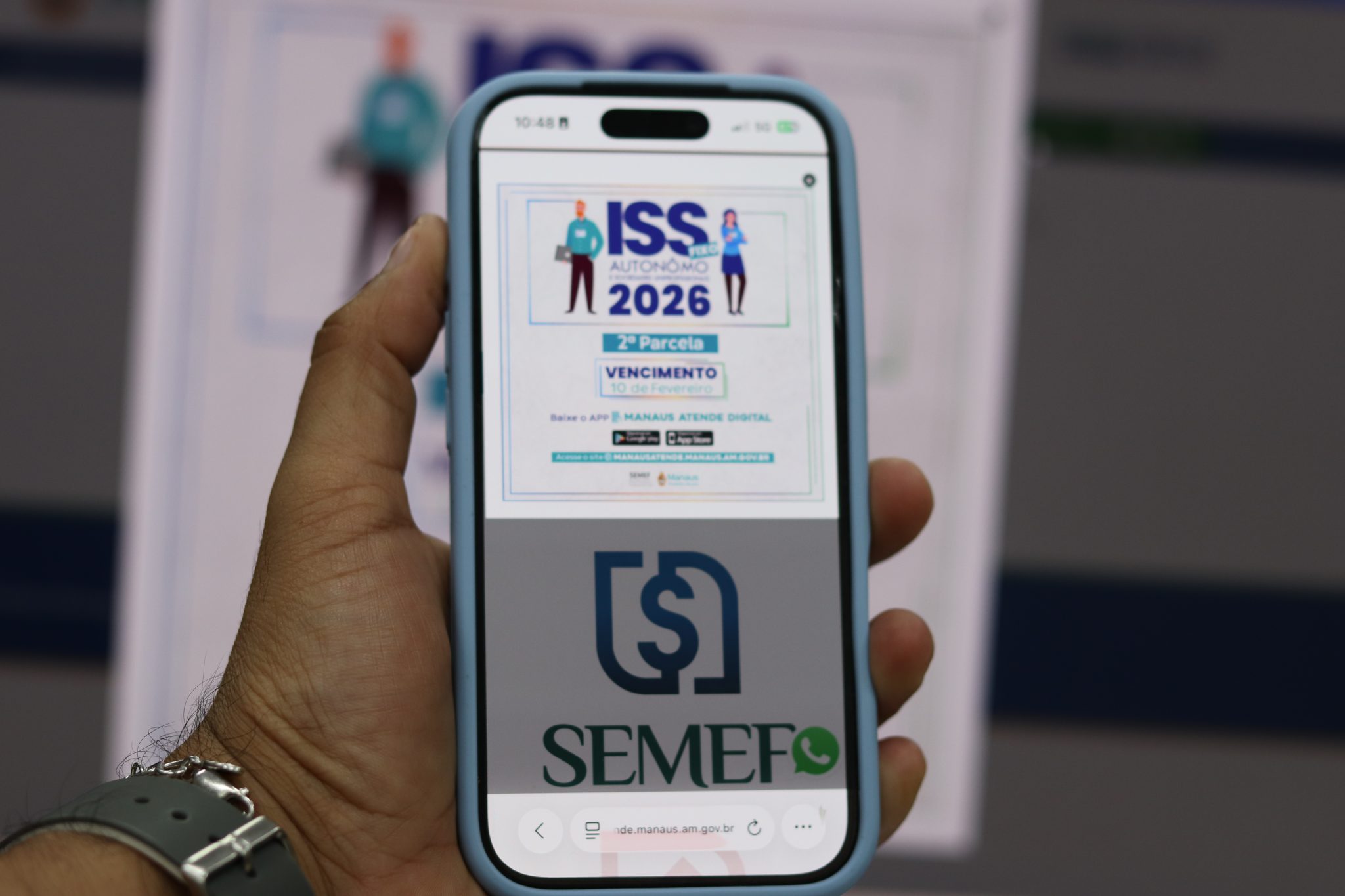 Mão segura celular em página do Manaus Atende Digital que garante desconto de 2% para pagamento do ISS Fixo